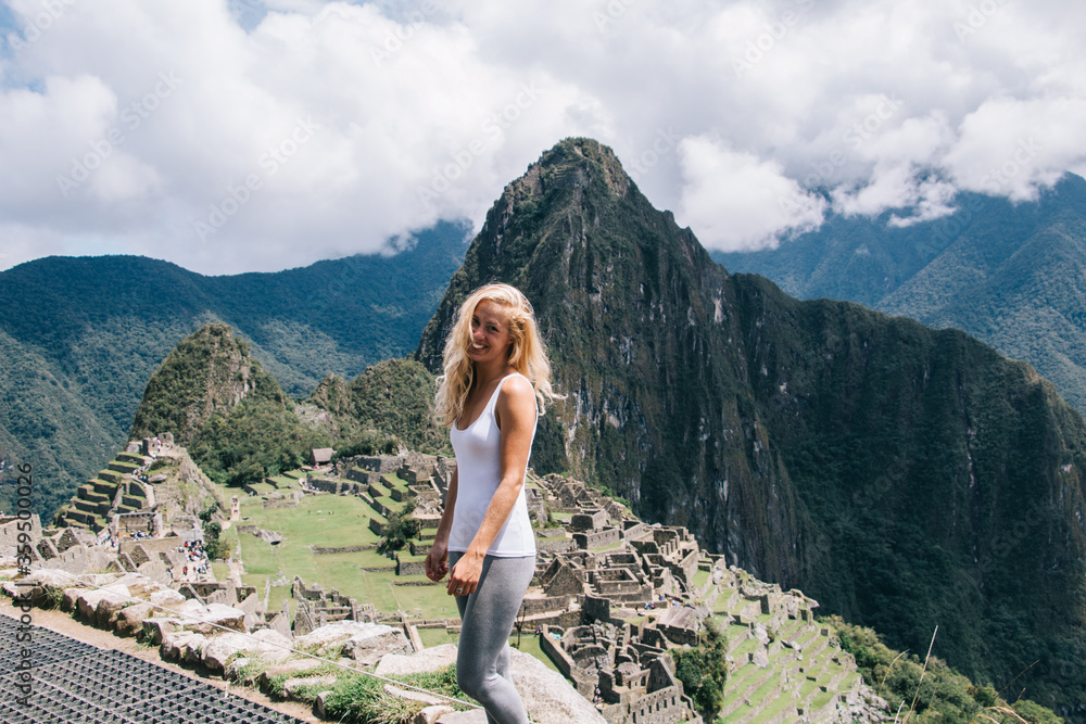 Obraz premium Half length portrait of cheerful female hiker with cutest smile on face enjoying trekking tour for exploring natural environment near Machu Picchu, carefree woman feeling happiness at green landscape