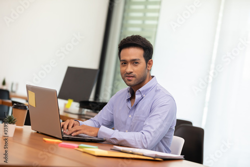 Portrait of Young business indian man working with laptop at office