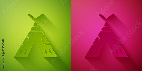 Paper cut Traditional indian teepee or wigwam icon isolated on green and pink background. Indian tent. Paper art style. Vector Illustration