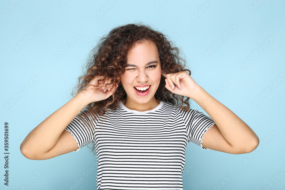 Young american girl closing ears by fingers on blue background Young american girl closing ears by fingers on blue background