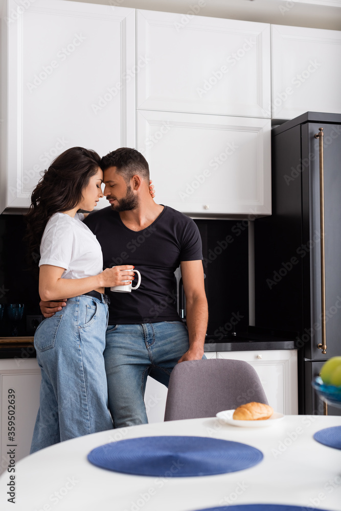 selective focus of beautiful girl holding cup and standing with boyfriend in kitchen selective focus of beautiful girl holding cup and standing with boyfriend in kitchen