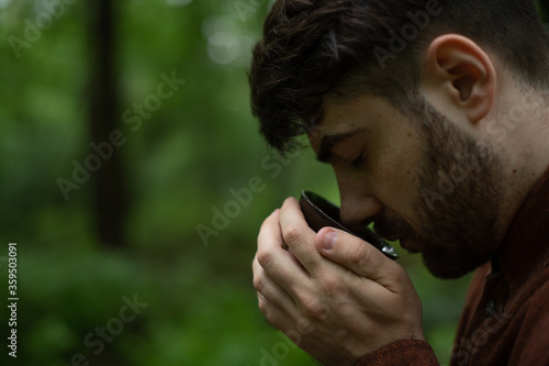 Side view of bearded man smelling tea bowl in summer forest  photo