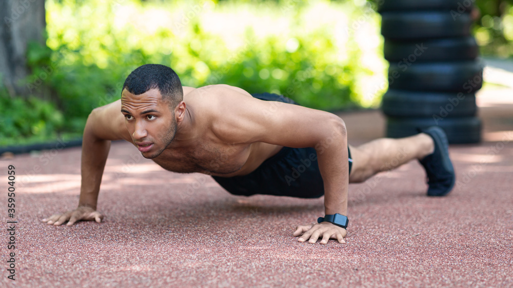 Shirtless muscular black guy performing push ups on jogging track at city park Shirtless muscular black guy performing push ups on jogging track at city park