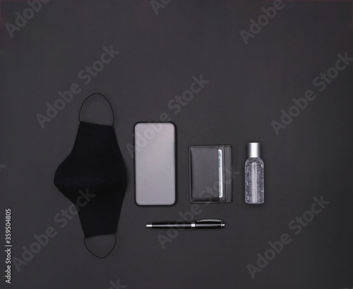 Travel accessories set on black background: face mask, antibacterial gel, cell phone, ballpoint pen and card holder. Top view point. photo