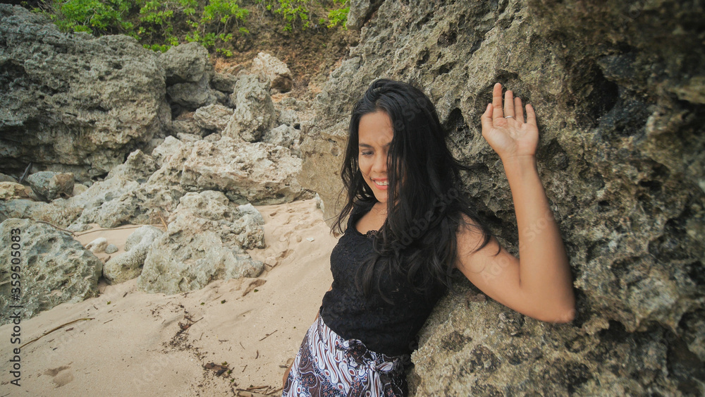 Indonesian girl posing on a beautiful and rocky beach in Bali. Idonezia. Indonesian girl posing on a beautiful and rocky beach in Bali. Idonezia.