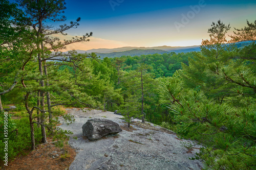 Exposed rock face with large boulder at sunset.