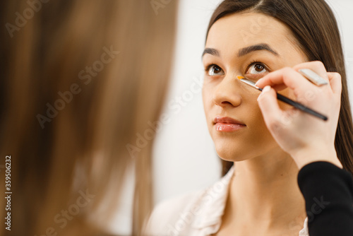 Cosmetician applies makeup on a woman's face