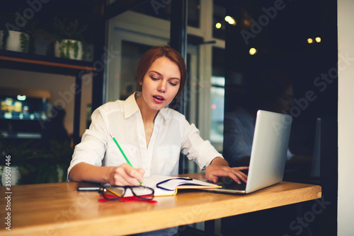 Concentrated female administrative manager using database information from cv of coworkers making financial report of salaries working using laptop computer and wireless connection to internet