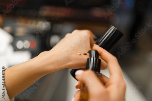 Woman choosing concealer tone in cosmetics store