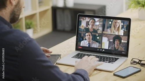 Back view of businessman joining a remote call with multi ethnic colleagues from home. Business Remote meeting or remote conference. Multi ethnic team video call.