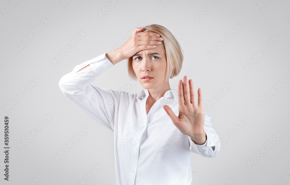 Blonde businesswoman showing STOP gesture on grey background Blonde businesswoman showing STOP gesture on grey background