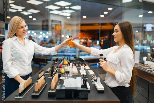 Fotografi Cosmetician at counter and woman, cosmetics store