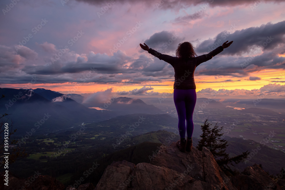 Adventurous Girl on top of a Rocky Mountain overlooking the beautiful Canadian Nature Landscape during a dramatic Sunset. Taken in Chilliwack, East of Vancouver, British Columbia, Canada. Adventurous Girl on top of a Rocky Mountain overlooking the beautiful Canadian Nature Landscape during a dramatic Sunset. Taken in Chilliwack, East of Vancouver, British Columbia, Canada.