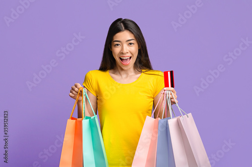 Big Sales. Excited Asian Girl Posing With Shopping Bags And Credit Card