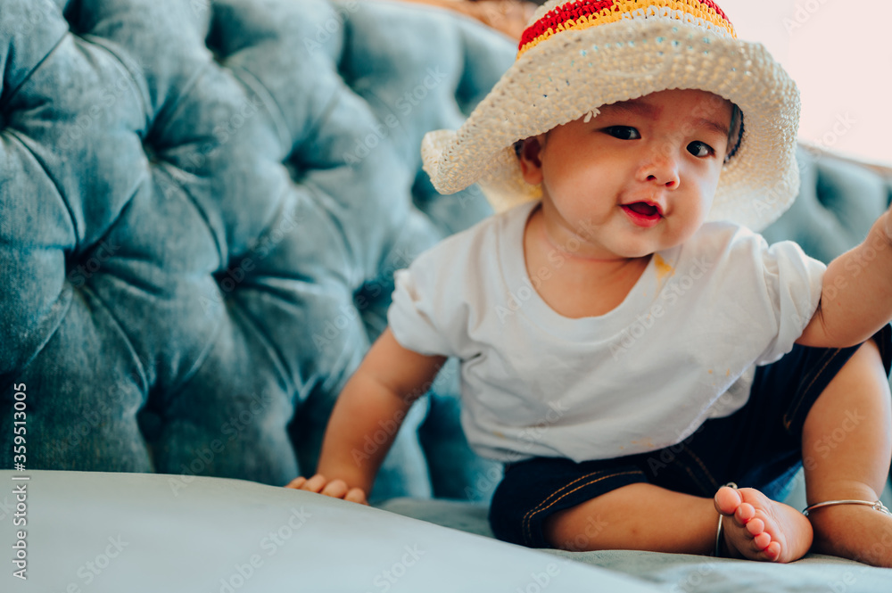 Portrait of asian a 7 months baby boy wearing a colorful cap sitting in sofa,summer fashion concept. Portrait of asian a 7 months baby boy wearing a colorful cap sitting in sofa,summer fashion concept.