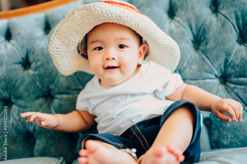 Portrait of asian a 7 months baby boy wearing a colorful cap sitting in sofa,summer fashion concept. Portrait of asian a 7 months baby boy wearing a colorful cap sitting in sofa,summer fashion concept.