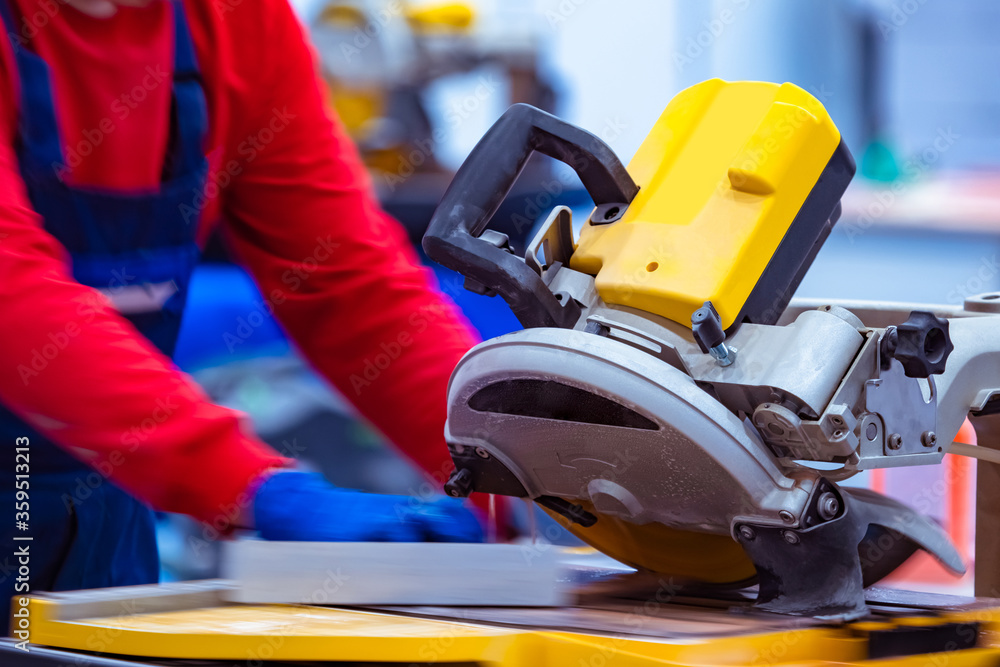 The master cuts a stone slab with a circular saw. Circular saw for cutting stone and tiles. A man next to a circular saw. A person works with tiles. Equipment for stone processing. Mason at work. The master cuts a stone slab with a circular saw. Circular saw for cutting stone and tiles. A man next to a circular saw. A person works with tiles. Equipment for stone processing. Mason at work.