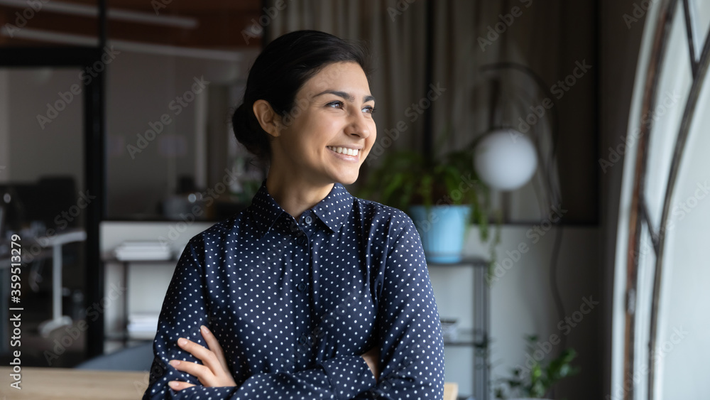 Successful Indian businesswoman, promoted employee headshot. Confident lady boss with arms crossed standing in modern office looking out the window feels proud by achievement, business goes up concept - obrazy, fototapety, plakaty 