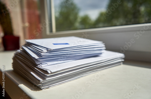 Pile of envelopes placed near the window at home