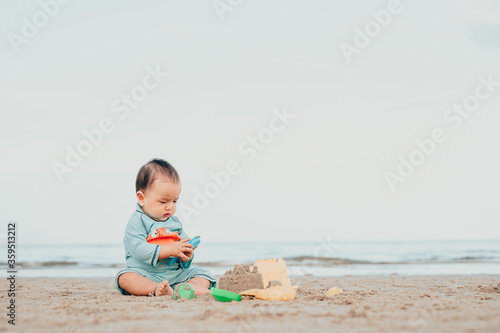 kid playing with sand on the beach by the sea. holidays with children near the ocean