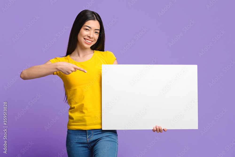 Place For Your Ad. Smiling Asian Girl Pointing At White Blank Placard Place For Your Ad. Smiling Asian Girl Pointing At White Blank Placard