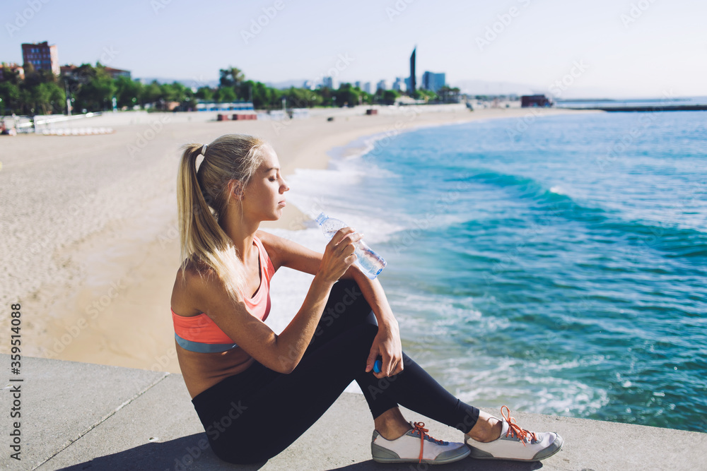 Fit women refreshing with energy drink after workout outdoors while
