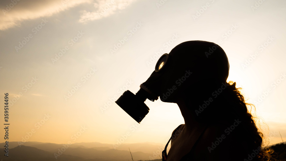 Silhouette of a woman with a gas mask during a sunset. Concept: ecology, there is no planet b