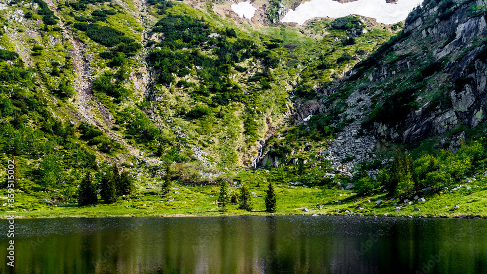 Landscape of a snow cauldron with a small waterfall flowing into the pond Landscape of a snow cauldron with a small waterfall flowing into the pond
