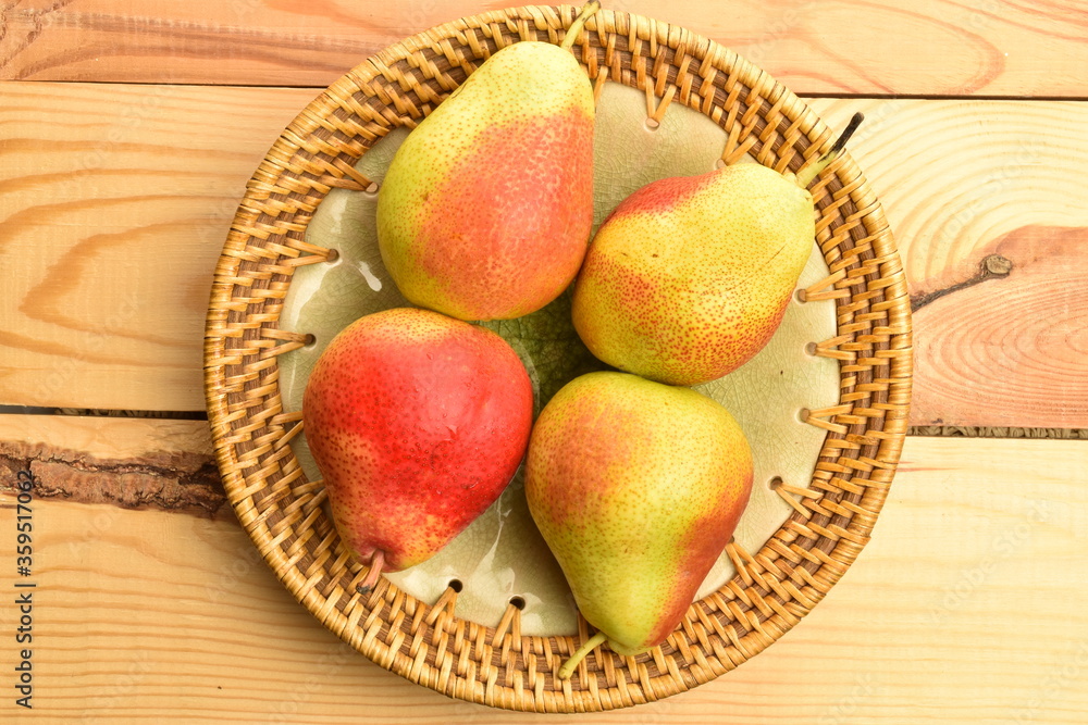 Organic juicy pears on a ceramic plate, close-up, on a wooden table.