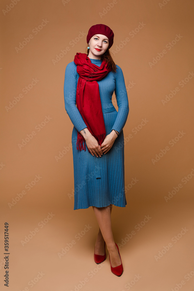 Full length stock studio photo of an attractive romantic lady wearing blue cotton dress with belt on waist and red accessories like hat, scarf and high heels. She is wearing red lipstick on and Full length stock studio photo of an attractive romantic lady wearing blue cotton dress with belt on waist and red accessories like hat, scarf and high heels. She is wearing red lipstick on and