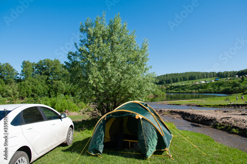 the tent stands on the banks of the river on a sunny day