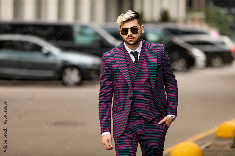 man in glasses and violet luxery three-piece suit, bow tie posing on the street