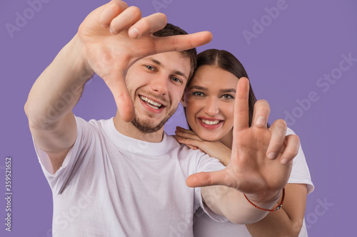 Beautiful young couple is making frame, looking at camera