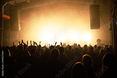 crowd in front of a stage at a music festival in the light of spotlights. viewers awaiting the show. concert banner. bluer