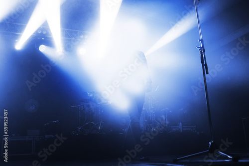 singer in the blue light of spotlights on the stage of a music festival. the concert lead goes to the microphone. bluer