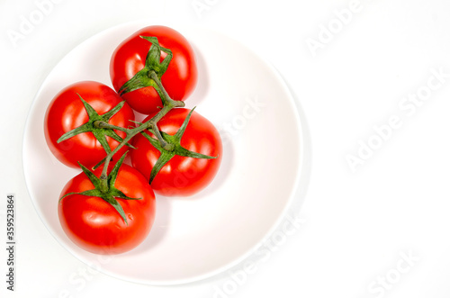 branch of red tomatoes on a white plate © Вячеслав 