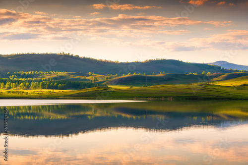 Green muntains at sunset and their reflections in the lake. Beautiful summer landscape. South Ural, Russia © smallredgirl