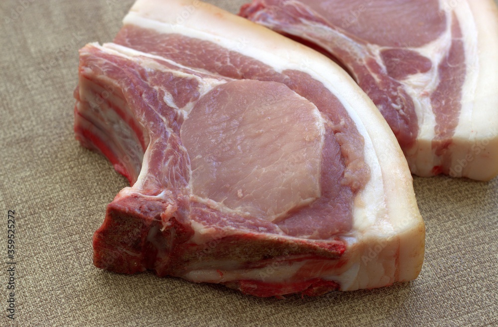 Raw pork steaks prepared for frying in a pan are on the counter in the market