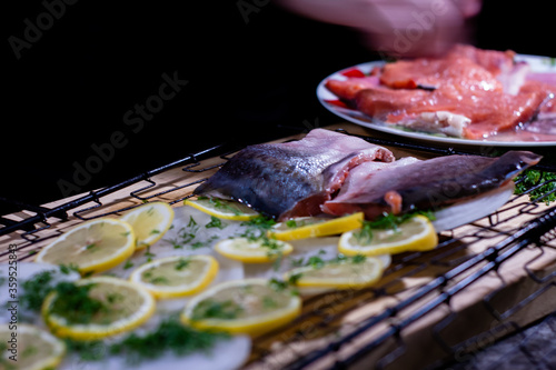 the cook puts pieces of delicious red fish on the grill with onions and lemon and herbs