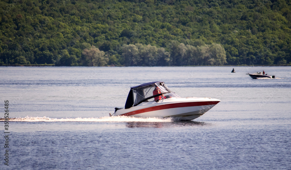 Fototapeta premium two small boats with motors are floating on a wide river