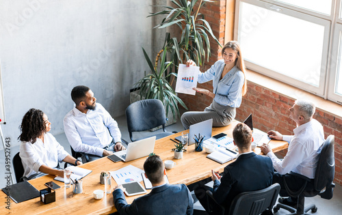 Businesswoman Showing Data Charts To Employees During Meeting In Office