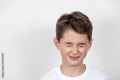 Obraz na płótnie Teenage boy in white shirt. Portrait in studio. Funny faces. w salonie
