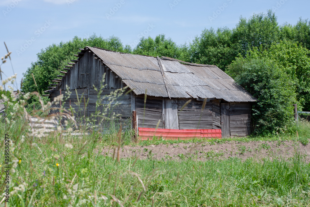 an old wooden barn in a field. summer. an old wooden barn in a field. summer.