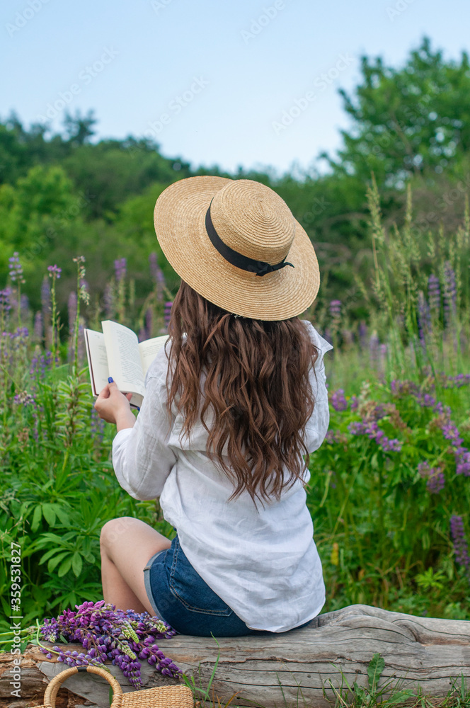 Pretty elegant girl reading book relax on nature field of flowers