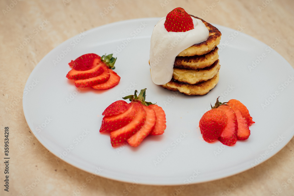 Delicious homemade pancakes with strawberries on plate on a light background Delicious homemade pancakes with strawberries on plate on a light background