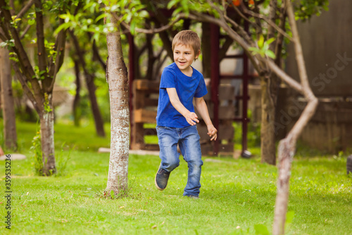 The child is running along the lawn between a trees