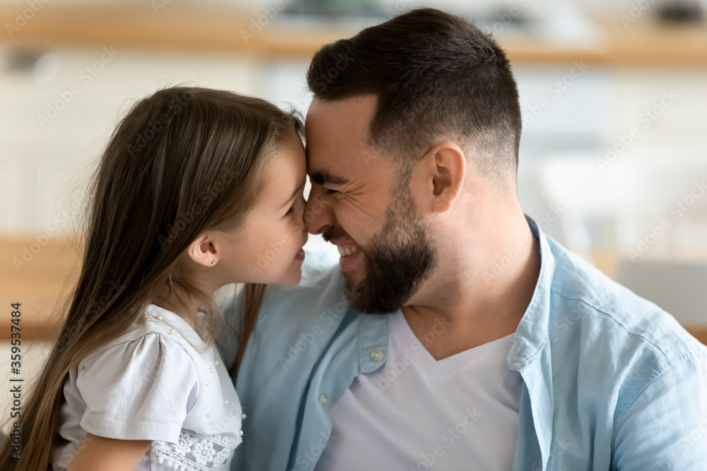Close up young handsome father happily touch noses with daughter at home. Happy smiling bearded dad hugging preschool girl having fun free time in living room. Close up young handsome father happily touch noses with daughter at home. Happy smiling bearded dad hugging preschool girl having fun free time in living room.