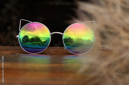 Sunglasses with a dandelion blossom on a dark background-the concept of travel and good summer days. © MARYIA