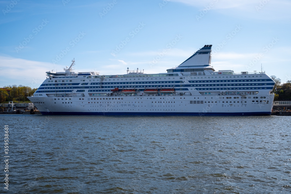 Large white passenger RORO-ferry with blue stripes docked at the harbor.