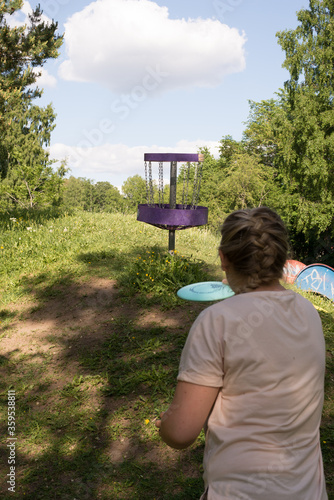 Girl throwing disc golf against basket